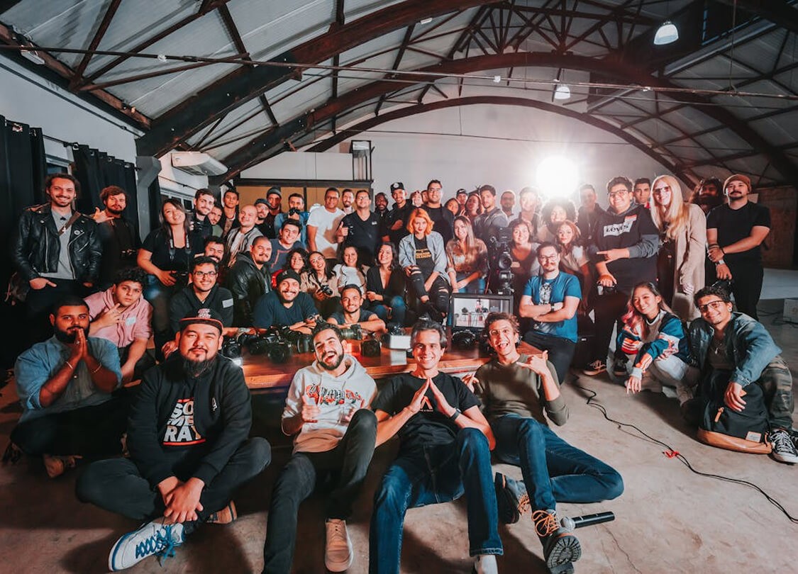 Skupinová fotografie týmu v industriálním prostoru s klenutým stropem.
